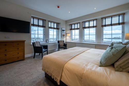 a bedroom with a large bed with a desk and windows at The Waterfront in Anstruther