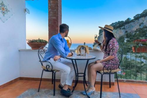 Un uomo e una donna seduti a un tavolo con l'oceano sullo sfondo di Villa Mare ad Amalfi