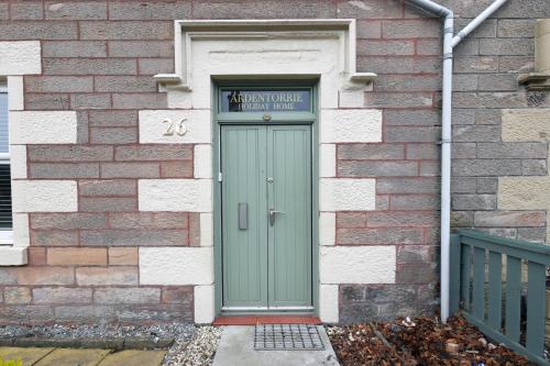 a green door on a brick building with a sign above it at Ardentorrie Holiday Home in Inverness