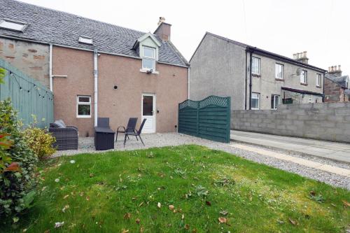 a yard with a chair in front of a house at Ardentorrie Holiday Home in Inverness