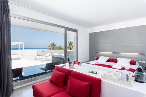 a bedroom with a red couch and a large window at Hotel Spa Calagrande Cabo de Gata in Las Negras