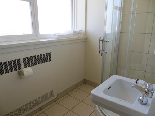 a bathroom with a sink and a toilet and a window at Athabasca Valley Inn & Suites in Hinton