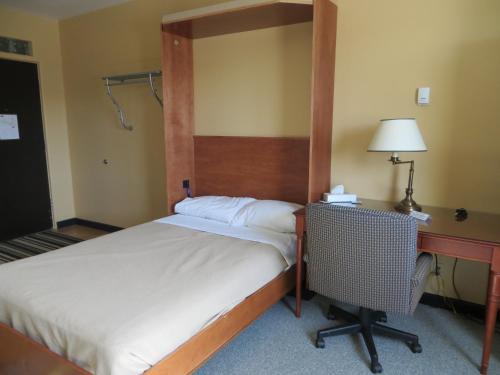 a bedroom with a bed with a desk and a bed sidx sidx sidx at Athabasca Valley Inn & Suites in Hinton