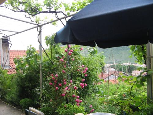 a garden with pink flowers and an umbrella at Guesthouse Panorama in Mostar