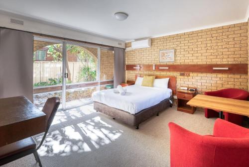 a bedroom with a bed and a table and chairs at Colac Mid City Motor Inn in Colac