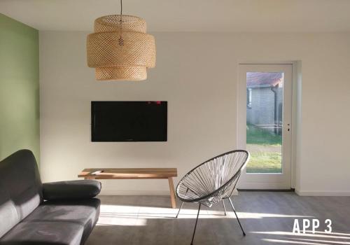 Una sala de estar con un sofá, una mesa y un televisor. en Tussen Dijken, en Hollum