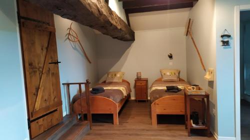 a bedroom with two beds and a wooden door at La Grange de Champagnac in Yvrac-et-Malleyrand