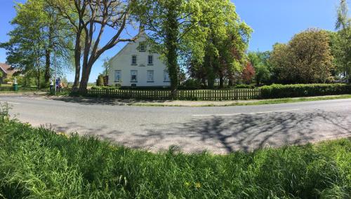 a white house with a fence on the side of a road at Steinhaus Hof in Bunde