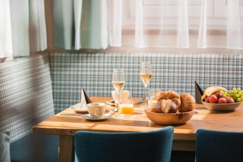a wooden table with food and glasses of wine at S'Kathrina - Appartements in Schattwald