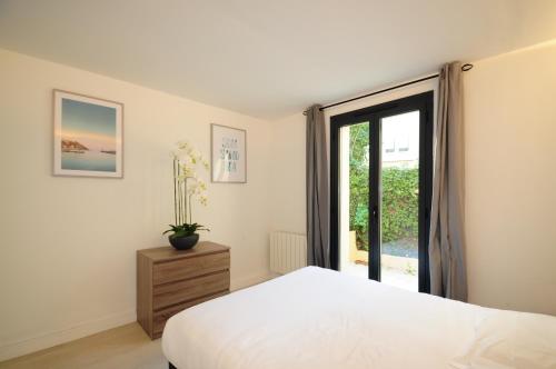 ein Schlafzimmer mit einem weißen Bett und einem Fenster in der Unterkunft Les Volets Bleus in Nizza