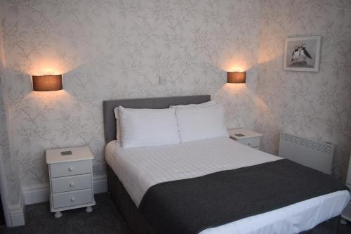 a bedroom with a bed with two night stands and two lamps at Cedar House, formerly Shamrock House in Llandudno