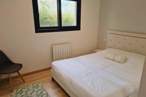 1 dormitorio con 1 cama, 1 silla y 1 ventana en LA CASA DE PECHABOU, en Péchabou