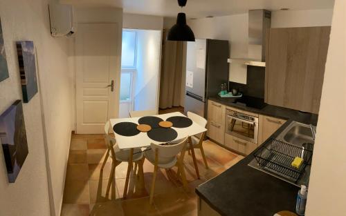une petite cuisine avec une table et des chaises blanches dans l'établissement Maison de village au pays des lavandes à Valensole, à Valensole