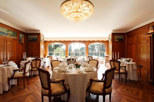 une salle à manger avec des tables et des chaises ainsi qu'un lustre dans l'établissement Château Des Bondons EI, à La Ferté-sous-Jouarre