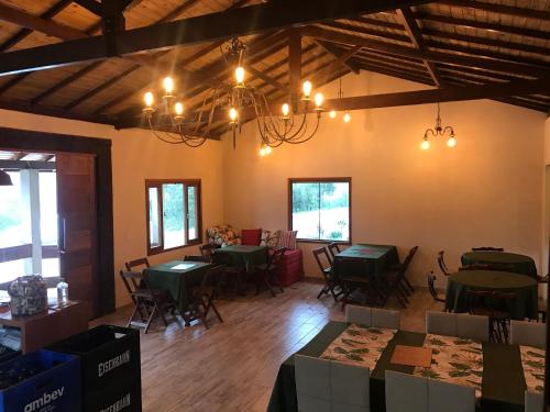 a dining room with green tables and chairs and chandeliers at Chalés do Recanto in São João del Rei