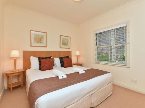 a bedroom with a large bed and a window at Villa 2br Provence Villa located within Cypress Lakes Resort in Pokolbin