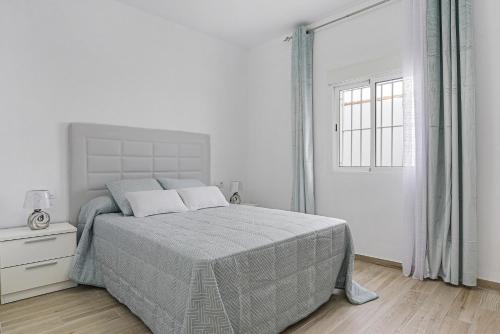 a white bedroom with a bed and a window at Casa Caramelo in La Muela