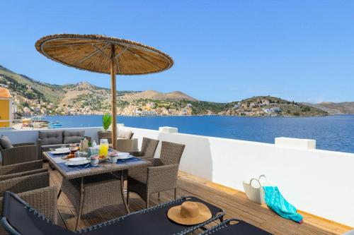 a table and chairs with an umbrella on a deck at Rementzo Apartment in Symi