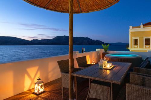 a table with an umbrella on a deck with the ocean at Rementzo Apartment in Symi