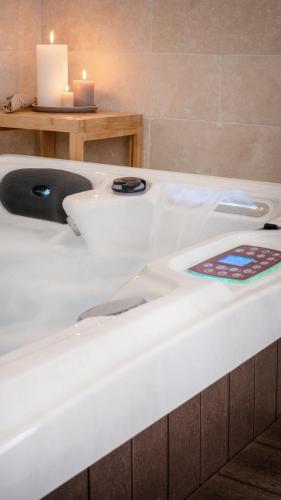 La salle de bains est pourvue d'une baignoire blanche avec deux bougies. dans l'établissement L'Ostal - Bed & Breakfast - Chambres et suites de 25 à 40m2 - Spa, à Saint-Hilaire-dʼOzilhan