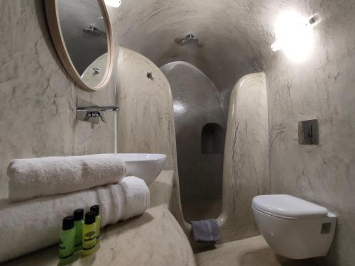 W łazience znajduje się umywalka, toaleta i lustro. w obiekcie Dreamer's secret villa w mieście Emporio