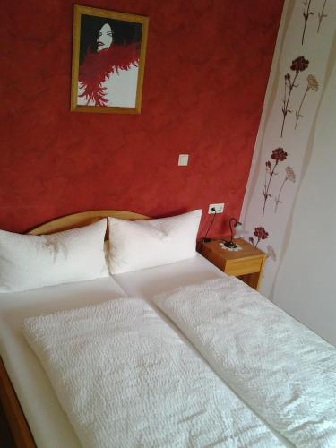 a bedroom with a white bed with a red wall at Lug ins Land Wachsenberg in Neusitz