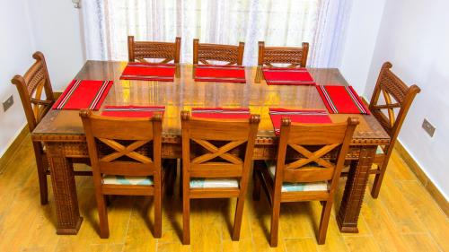 a wooden dining room table with chairs and red napkins at Golden Duranta Villas in Ukunda