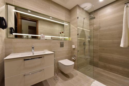 a bathroom with a toilet sink and a shower at Swiss-Belsuites Admiral Juffair in Manama