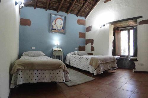 a bedroom with two beds and a window at Casa Rural La Fuente de la Flora in Santa Lucía