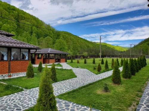 a garden with trees and a building in the background at Pensiunea Perla Râușor in Rîuşor