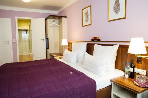 a hotel room with a purple bed and a bathroom at Hotel Elch in Nuremberg