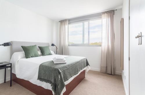 Un dormitorio blanco con una cama y una ventana. en Azvalia - Edificio Parque, en El Puerto de Santa María