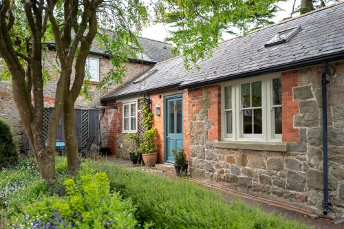 een bakstenen huis met een blauwe deur en ramen bij Courtyard Cottage in Oswestry