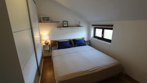niewielka sypialnia z łóżkiem z niebieskimi poduszkami w obiekcie Apartment Vdovjak w mieście Malinska
