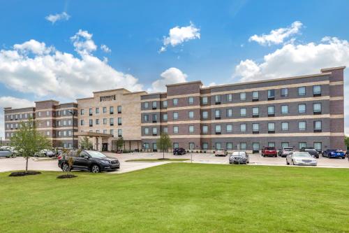 a large building with cars parked in a parking lot at Staybridge Suites Grand Prairie Near Epic Central by IHG in Grand Prairie