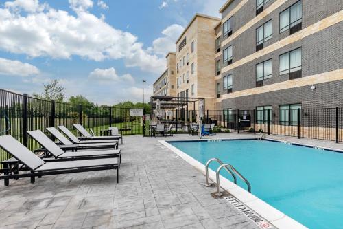 a swimming pool with lounge chairs next to a building at Staybridge Suites Grand Prairie Near Epic Central by IHG in Grand Prairie
