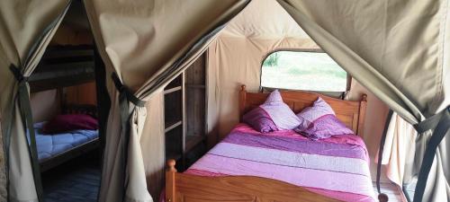 Cama en tienda de campaña con almohadas moradas y blancas en Camping des vignes, en Dun