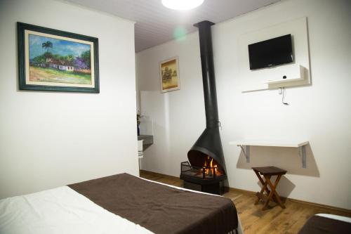 een slaapkamer met een bed en een open haard. bij Pousada Canto Verde in São Bento do Sapucaí