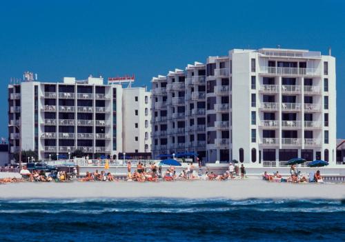 a group of people sitting on the beach in front of buildings at Bal Harbour Hotels in Wildwood Crest