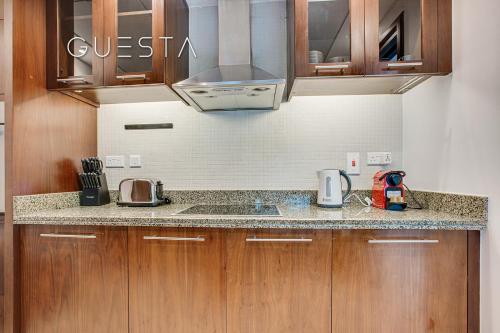 a kitchen with wooden cabinets and a counter top at Marina Promenade - Paloma Tower, Dubai Marina in Dubai