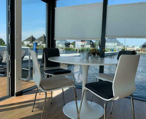 uma mesa e cadeiras brancas com vista para a água em Houseboat - Sneekermeer em Offingawier
