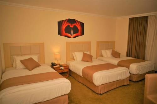 
a hotel room with two beds and two lamps at Silk Road Hotel in Wadi Musa
