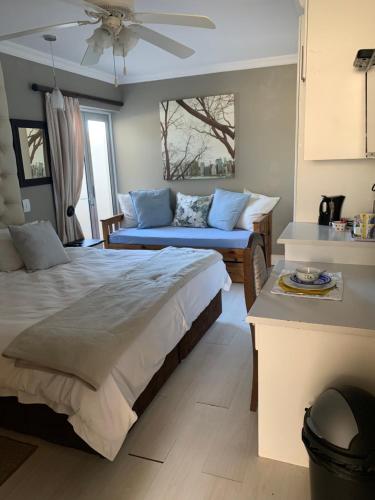 een slaapkamer met een bed en een bank erin bij Sharwood Place in Port Elizabeth