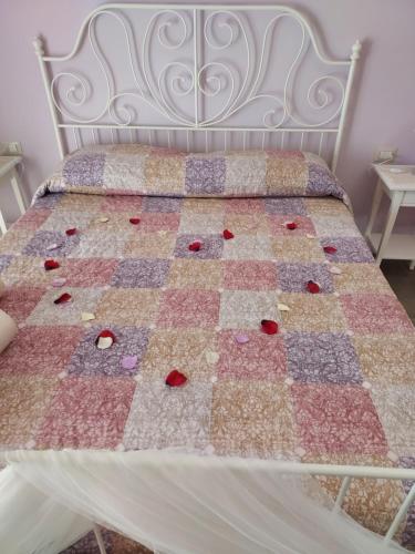 a bed with a quilt on it with roses on it at B&B Petra Hercules in Torre Annunziata
