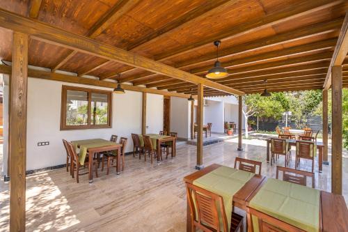 un patio al aire libre con techos de madera, mesas y sillas en Ayris Hotel Çıralı, en Cıralı