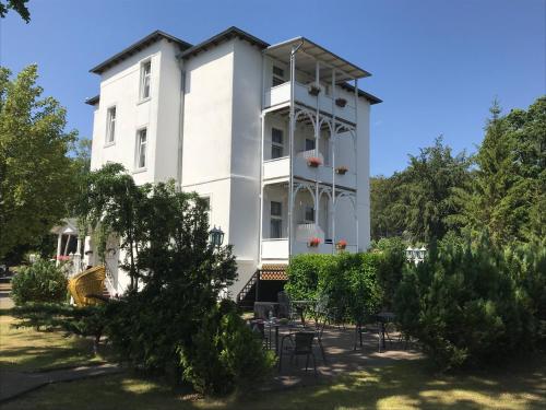 a white building with trees in front of it at Pension Villa Frohsinn Sellin auf Rügen in Ostseebad Sellin