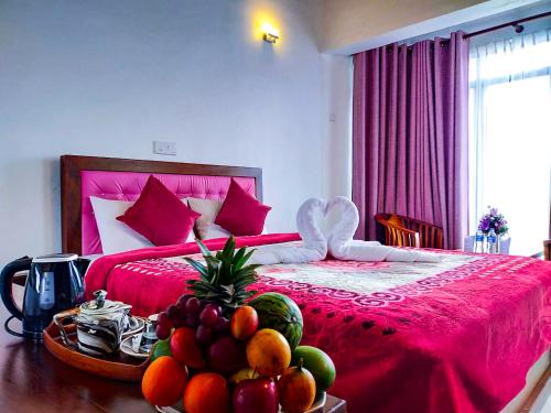 a bedroom with a red bed with a bowl of fruit at Lake View Holiday Resort in Nuwara Eliya