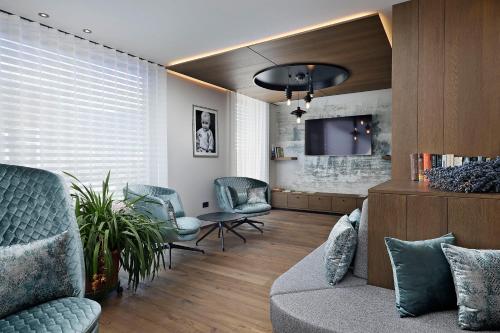 a living room with a couch and chairs and a tv at Appartement-Hotel Beatenhof in Tirolo