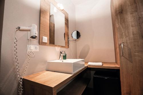 La salle de bains est pourvue d'un lavabo blanc et d'un miroir. dans l'établissement Der Schumi Landgasthof, à Reipersdorf