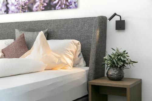 a bed with white pillows and a lamp on a table at Appartement-Hotel Beatenhof in Tirolo
